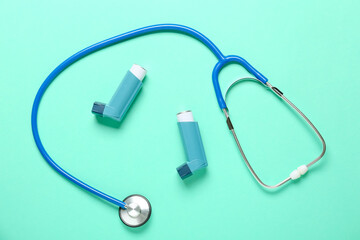 Inhalers and stethoscope on color background