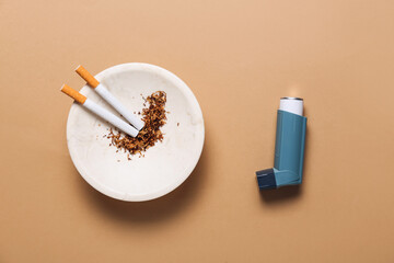 Inhaler and cigarettes on color background