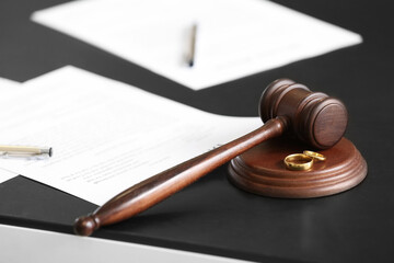 Judge's gavel with wedding rings on table in office