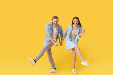 Happy young couple dancing on color background