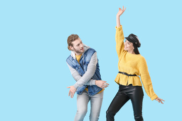 Happy young couple dancing on color background