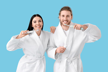 Young couple brushing teeth on color background