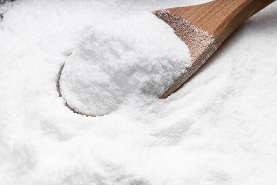 wooden spoon with dextrose sugar close up on pile