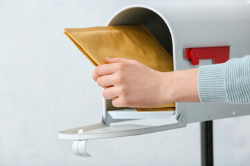 Woman getting letters from box on light background