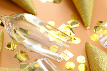 Champagne glass with party cones and confetti on color background, closeup