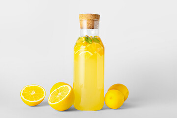 Bottle of tasty cold lemonade with mint on light background