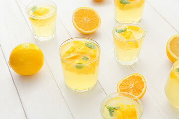 Glasses of tasty cold lemonade on light wooden background