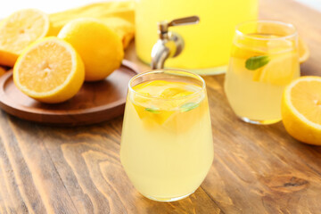 Jar and glasses of tasty cold lemonade on wooden background