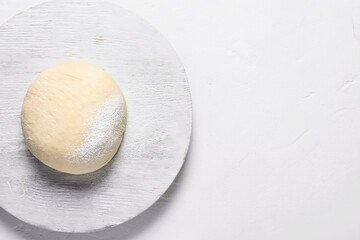 Board with fresh dough and flour on white background