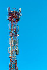 Vertical photo of the cell tower and radio communication painted red and white against the...