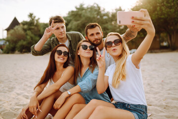 Group of people doing selfie with phone at the beach. Young friends enjoy summer party together....