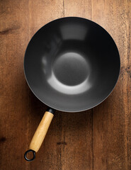 Traditional Asian Wok pan for stir fry cooking with wooden handle on rustic table