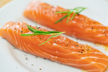 Salmon steak a piece of fresh home cooking with rosemary, olive oil, black pepper and himalayan salt on a white plate. Focus select and blur close up and Macro photography.