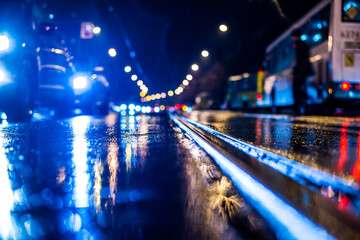 Rainy night in the big city, stream of cars traveling along the avenue and pedestrians on the road....