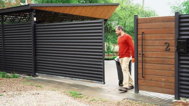 The homeowner remotely opens the gate to roll out the dumpster.