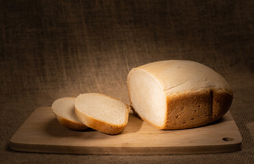 Healthy homemade white bread on wooden board under sunray. Baked in a bread maker.