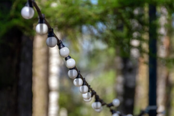 Selective focus. A garland of dirty white round-shaped light bulbs.