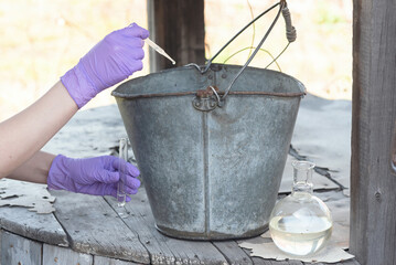 Well water pollution concept. Scientist is taking a water sample for the test close up.