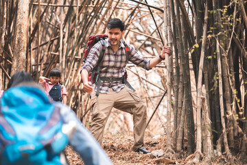 Fototapeta premium Group Hiker team helping family climb up timber. Traveler teamwork and family relax walking in outdoor lifestyle adventure and camping.