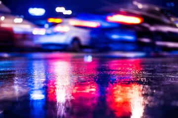 Rainy night in the big city, racing cars on the road. View from the level of asphalt