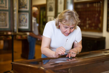 Mature woman visiting exposition of Art Museum with exhibits of antiquity