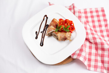 Stuffed meat with mushrooms baked with bacon on a white plate