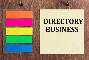 Directory business text on yellow paper on wooden background next to colored glue sticky notes