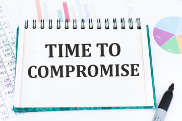 text TIME TO COMPROMISE written on notepad against the background of colored graphs. Business concept