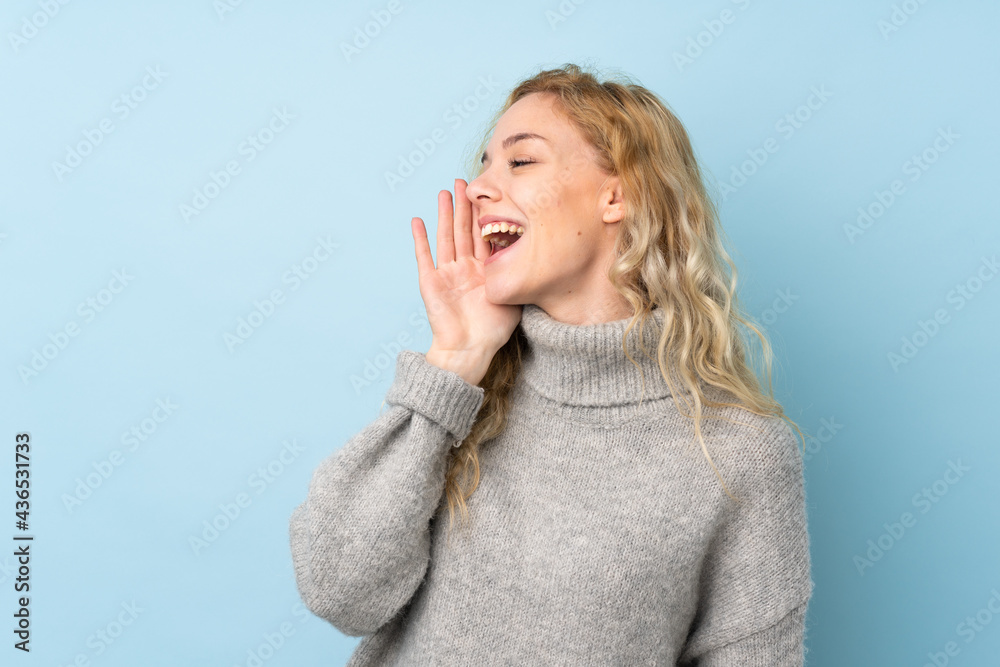 Poster Young blonde woman wearing a sweater isolated on blue background shouting with mouth wide open to the lateral