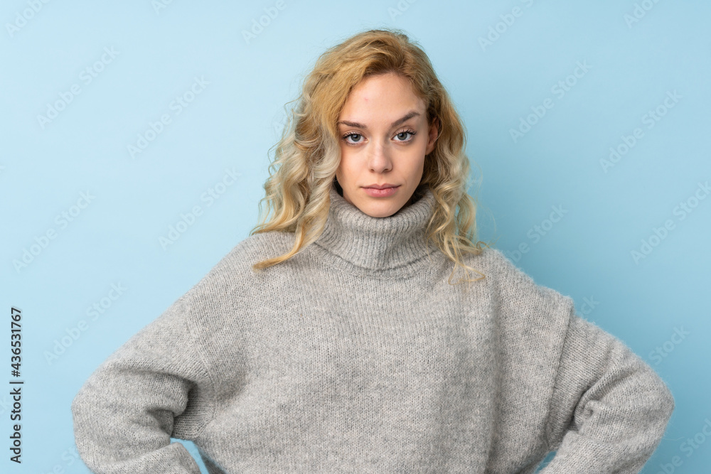 Poster Young blonde woman wearing a sweater isolated on blue background angry