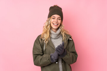 Young girl with winter hat isolated on pink background applauding