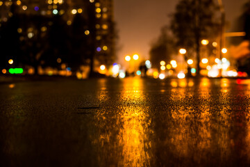 Rainy night in the big city, alley in the city park with walking people. View from the level of asphalt