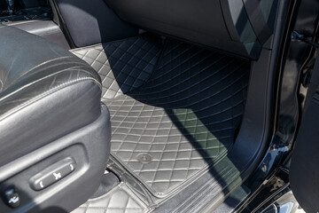 Close-up car floor mats of luxury leather, interior trim with white diamond stitching. Trim...