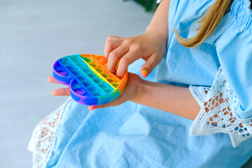 Child playing with rainbow pop it fidget toy. Push bubble fidget sensory toy - washable and...