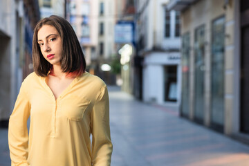 Young hispanic independent and confident woman in a urban Toledo, Spain street. Lifestyle streetwear portrait yellow color of year stylish 
