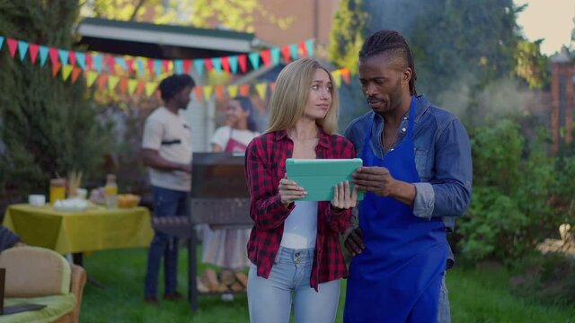 Portrait of African American confident man calming down sad Caucasian woman on backyard picnic. Handsome boyfriend talking with unsuccessful girlfriend startuper outdoors. Freelance and lifestyle