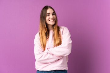 Obraz premium Young caucasian woman isolated on purple background looking up while smiling