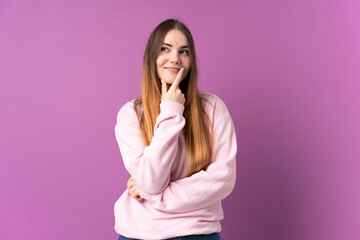 Young caucasian woman isolated on purple background looking to the side and smiling