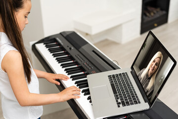 Fototapeta na wymiar Homeschool little young kid girl learning piano from computer connecting to internet music online class by school teacher. New normal lifestyle and education, student study at home concept.