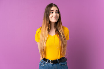 Young caucasian woman isolated on purple background making doubts gesture looking side