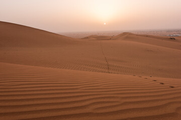 Fototapeta na wymiar Beautiful desert sunrise with sun visible and sand dooms with sand pattern & walk path