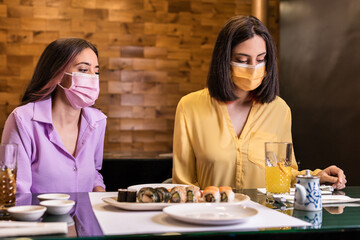 Young Hispanic woman eat sushi in a Japanese food restaurant. Lifestyle new normal dinner wearing...