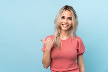 Fototapeta premium Teenager girl over isolated blue background pointing to the side to present a product