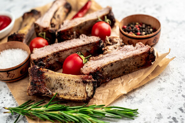 chopped pork ribs on the grill on a light stone background