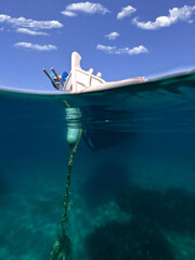 Underwater split photo of traditional fishing boat anchored near deep blue sea of picturesque port...