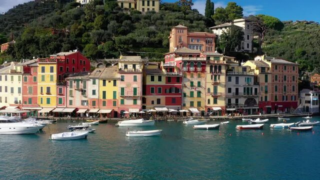 Harbor of Portofino in Italy. We can see boats and colorful houses in front of the mountain - aerial view with a drone 4K