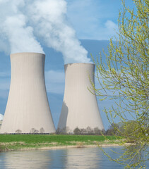 Branch with green leaves  against nuclear power plant.
