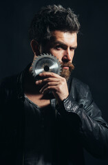 Bearded man in black leather jacket with saw-blade near beard. Man with circular saw. Closeup portrait.