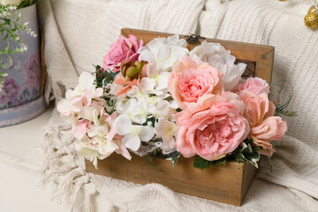 a wooden open box with pink plastic flowers stands on a light background