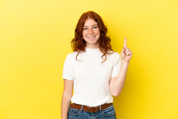 Teenager reddish woman isolated on yellow background showing and lifting a finger in sign of the best